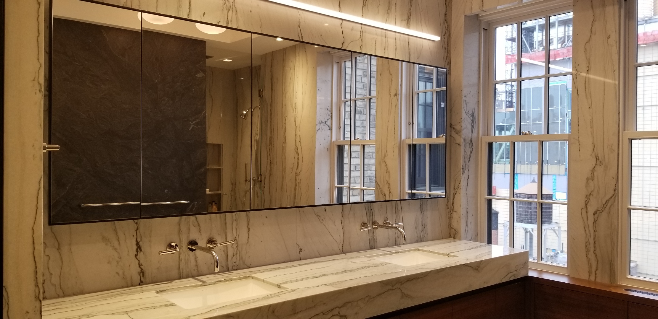 Cantilevered floating double vanity in reeded natural white oak with monolithic limestone counter